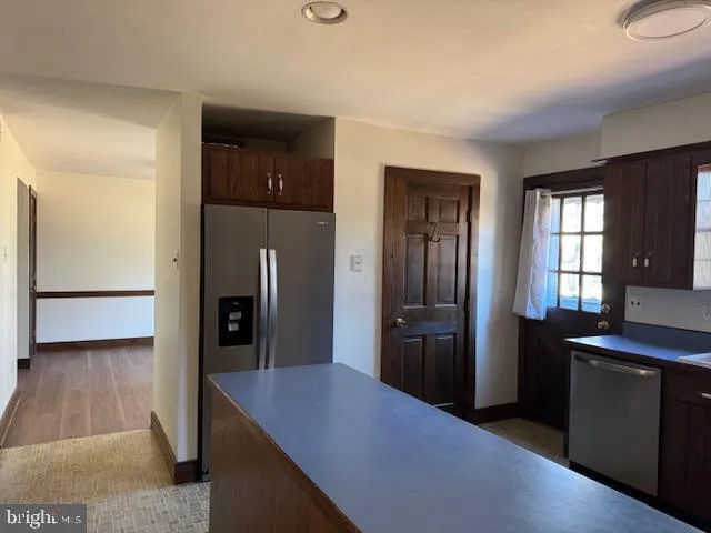 a kitchen with stainless steel appliances kitchen island granite countertop a refrigerator and a sink