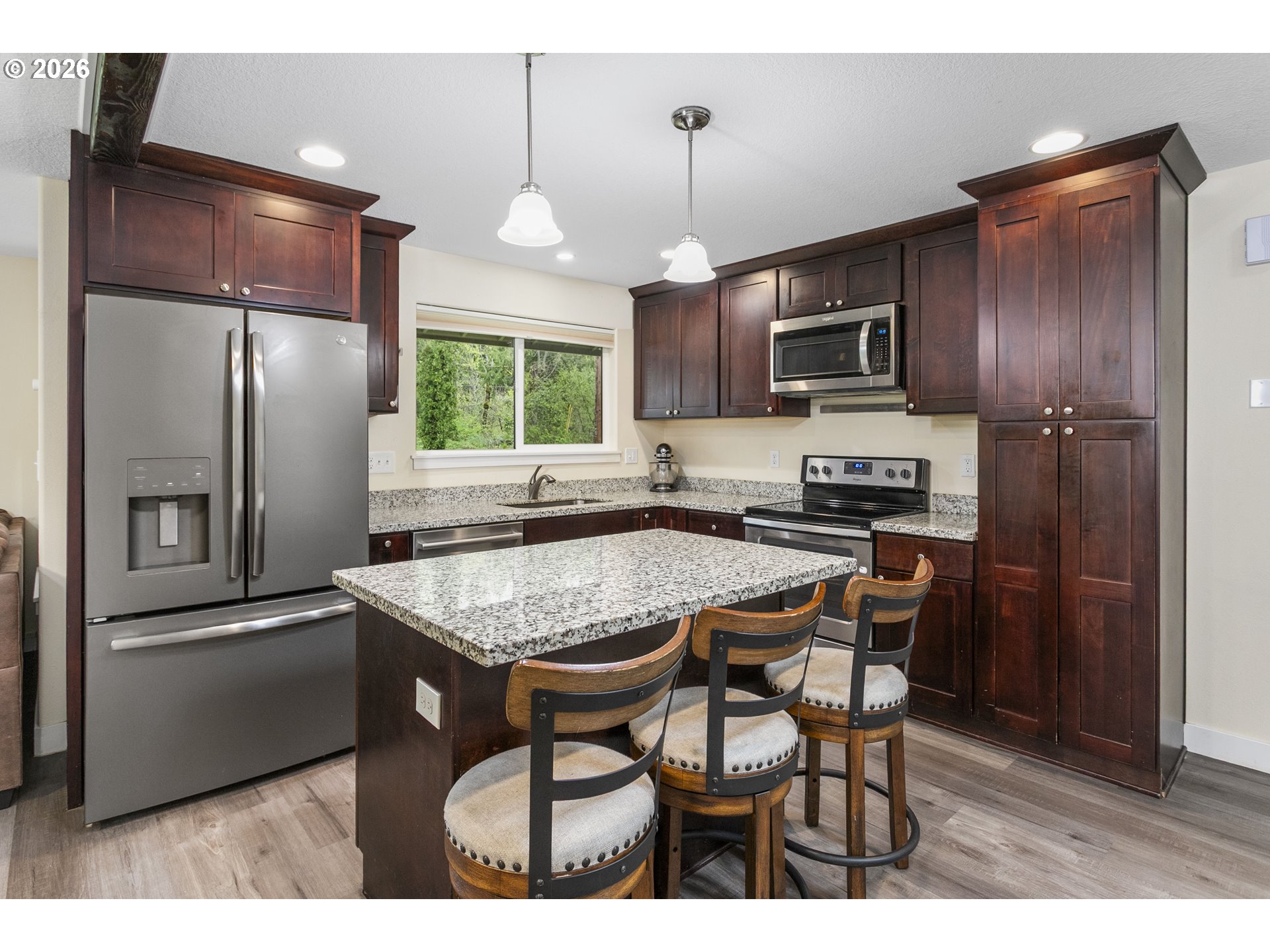 23575 East Gumjuwac Road Welches, OR 97067 - Photo 3 of 48 a kitchen with stainless steel appliances granite countertop a refrigerator a sink a stove a microwave a dining table and chairs