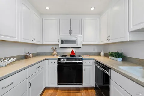 a kitchen with stainless steel appliances granite countertop a sink dishwasher and white cabinets