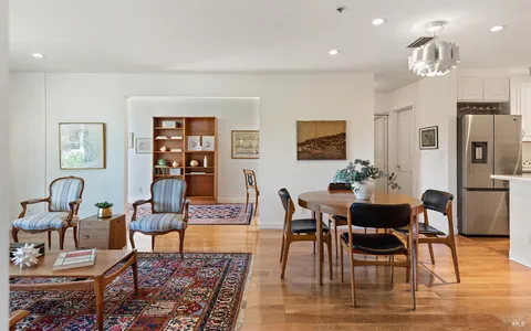 a living room with furniture couches and a dining table with wooden floor