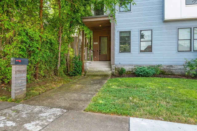 a view of a brick house with a large windows plants and large trees