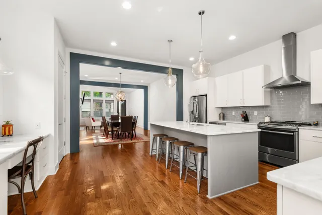 a kitchen with kitchen island a stove a refrigerator a sink dishwasher with a dining table and chairs with wooden floor