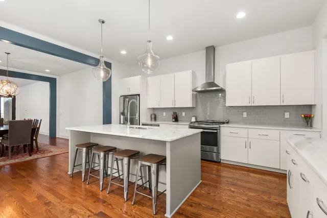 a kitchen with stainless steel appliances granite countertop a table chairs sink and cabinets