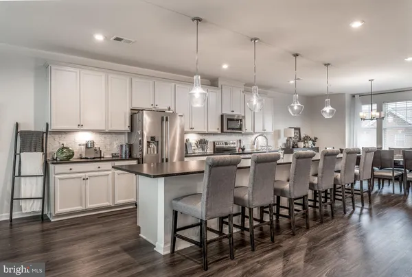 a kitchen with lots of white furniture appliances and wooden floor