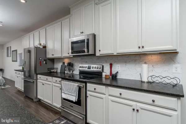 a kitchen with granite countertop white cabinets stainless steel appliances and a sink