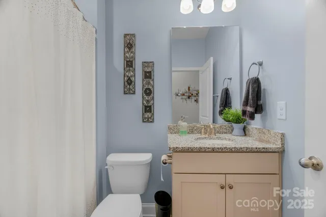 a bathroom with a granite countertop toilet sink and mirror