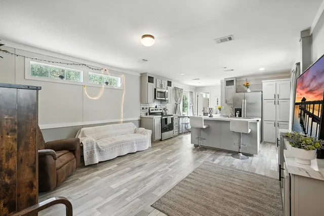 a living room with furniture kitchen view and a wooden floor