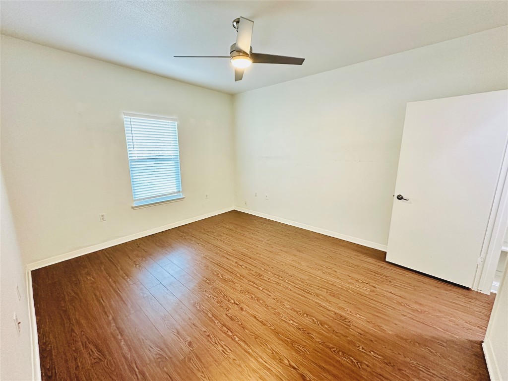 6301 Crumley Lane Austin, TX 78741 - Photo 15 of 39 an empty room with wooden floor chandelier fan and windows