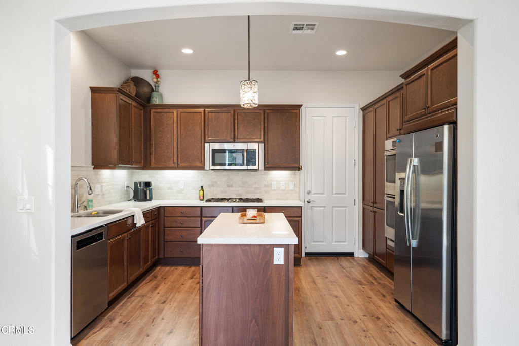 1655 Range Road Oxnard, CA 93036 - Photo 12 of 33 a kitchen with stainless steel appliances granite countertop a refrigerator a sink dishwasher a stove and white countertops with wooden floor