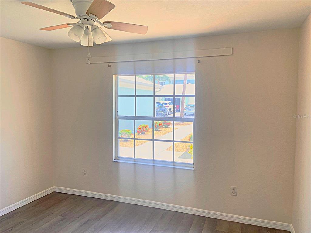 5771 Sabal Trace Drive, Unit 102 B5771 North Port, FL 34287 - Photo 27 of 37 an empty room with wooden floor fan and windows
