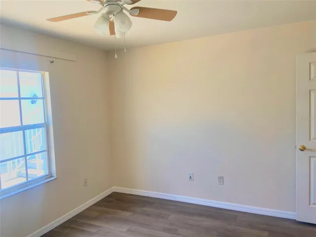 an empty room with a window and ceiling fan