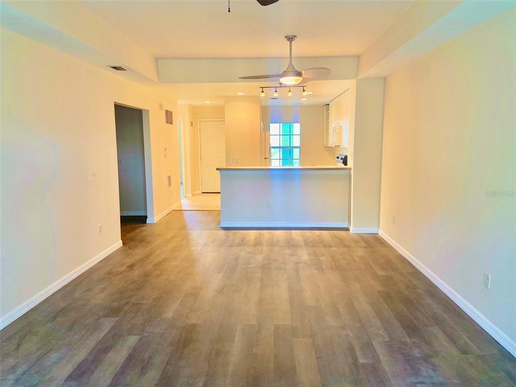 5771 Sabal Trace Drive, Unit 102 B5771 North Port, FL 34287 - Photo 7 of 37 a view of empty room with wooden floor and kitchen view