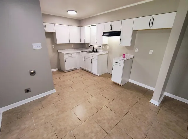a kitchen with a sink a stove a refrigerator and white cabinets