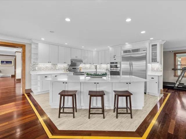 a kitchen with stainless steel appliances kitchen island granite countertop a stove a refrigerator and a dining table with wooden floor