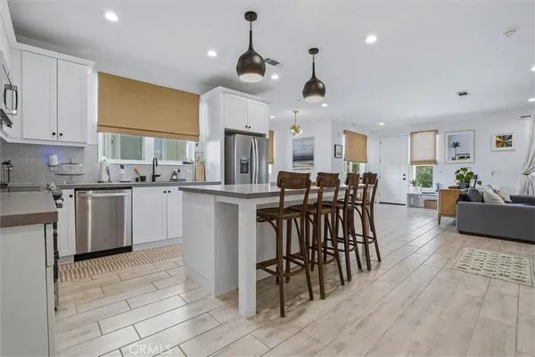 a kitchen with stainless steel appliances kitchen island granite countertop a stove a sink a dining table and chairs