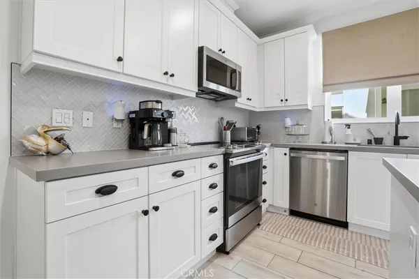a kitchen with white cabinets stainless steel appliances and sink