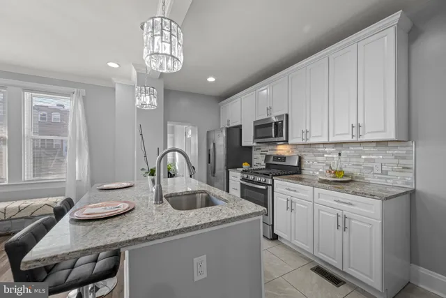 a kitchen with stainless steel appliances granite countertop a sink dishwasher stove and white cabinets with wooden floor