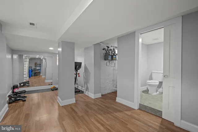 a view of a hallway with wooden floor and a bathroom