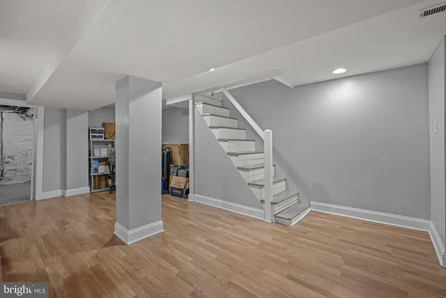 a view of an empty room with wooden floor and stairs