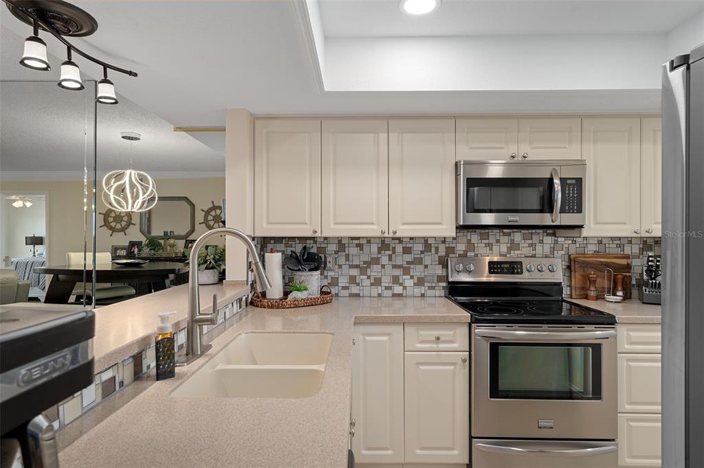 4550 Bay Boulevard, Unit 1211 Port Richey, FL 34668 - Photo 15 of 65 a kitchen with stainless steel appliances a stove sink microwave and cabinets