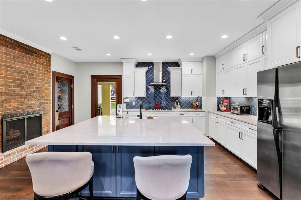 304 North Church Street Pilot Point, TX 76258 - Photo 14 of 40 a large kitchen with kitchen island a stove a sink a refrigerator and white cabinets with wooden floor