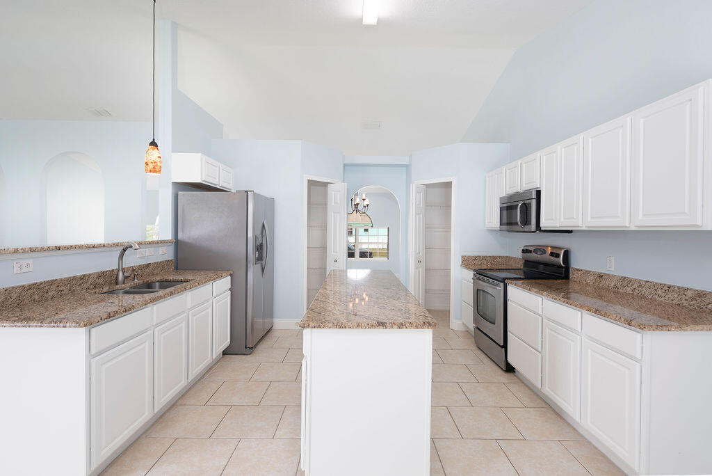 1815 Dragon Road Southeast Palm Bay, FL 32909 - Photo 12 of 41 a kitchen with stainless steel appliances granite countertop a sink stove and refrigerator
