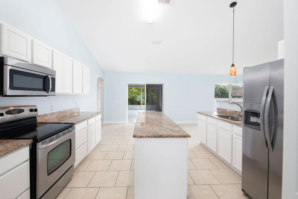 1815 Dragon Road Southeast Palm Bay, FL 32909 - Photo 13 of 41 a kitchen with granite countertop a sink a stove top oven and stainless steel appliances