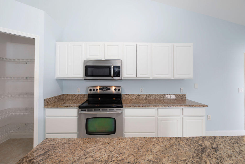 1815 Dragon Road Southeast Palm Bay, FL 32909 - Photo 14 of 41 a kitchen with white cabinets and appliances