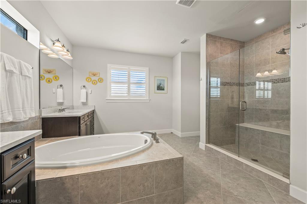 19157 Elston Way Estero, FL 33928 - Photo 23 of 50 a spacious bathroom with a granite countertop tub sink shower and mirror