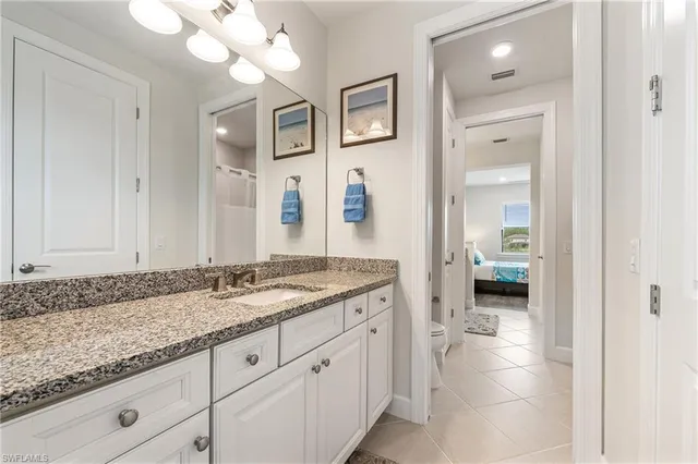 a en suite bathroom with a granite countertop sink and a mirror