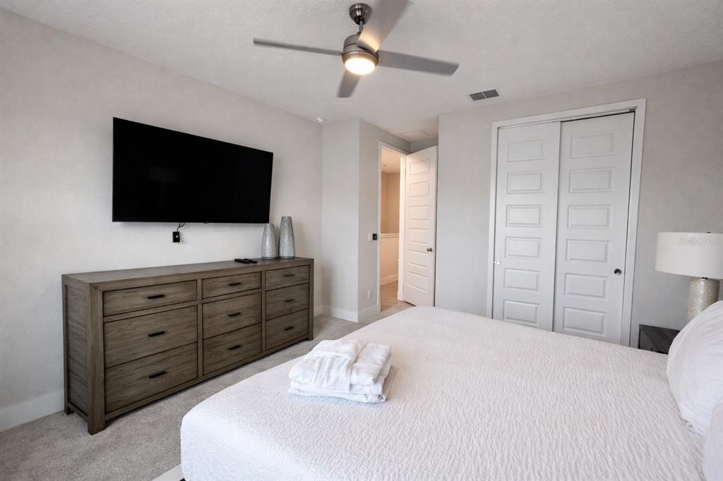 7909 Draw Street Reunion, FL 34747 - Photo 6 of 12 a bedroom with a bed a flat screen tv and a chandelier