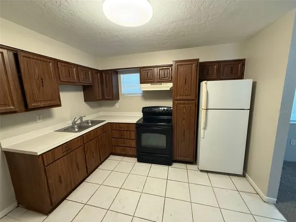 a kitchen with a refrigerator a stove top oven and cabinets