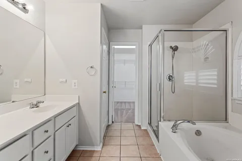 a bathroom with a tub sink shower and two mirror