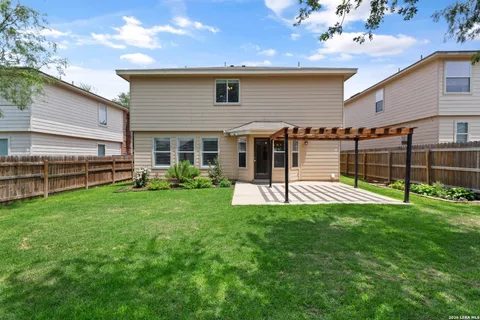 a view of a house with a yard and a large tree