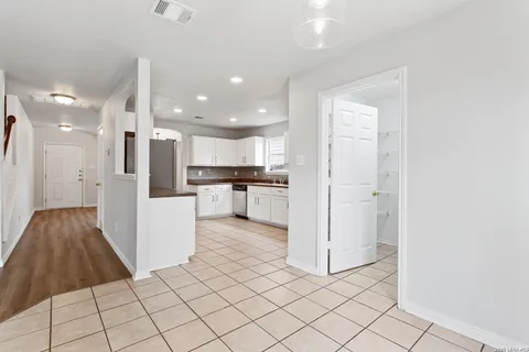 a view of kitchen view with refrigerator stove and white cabinets