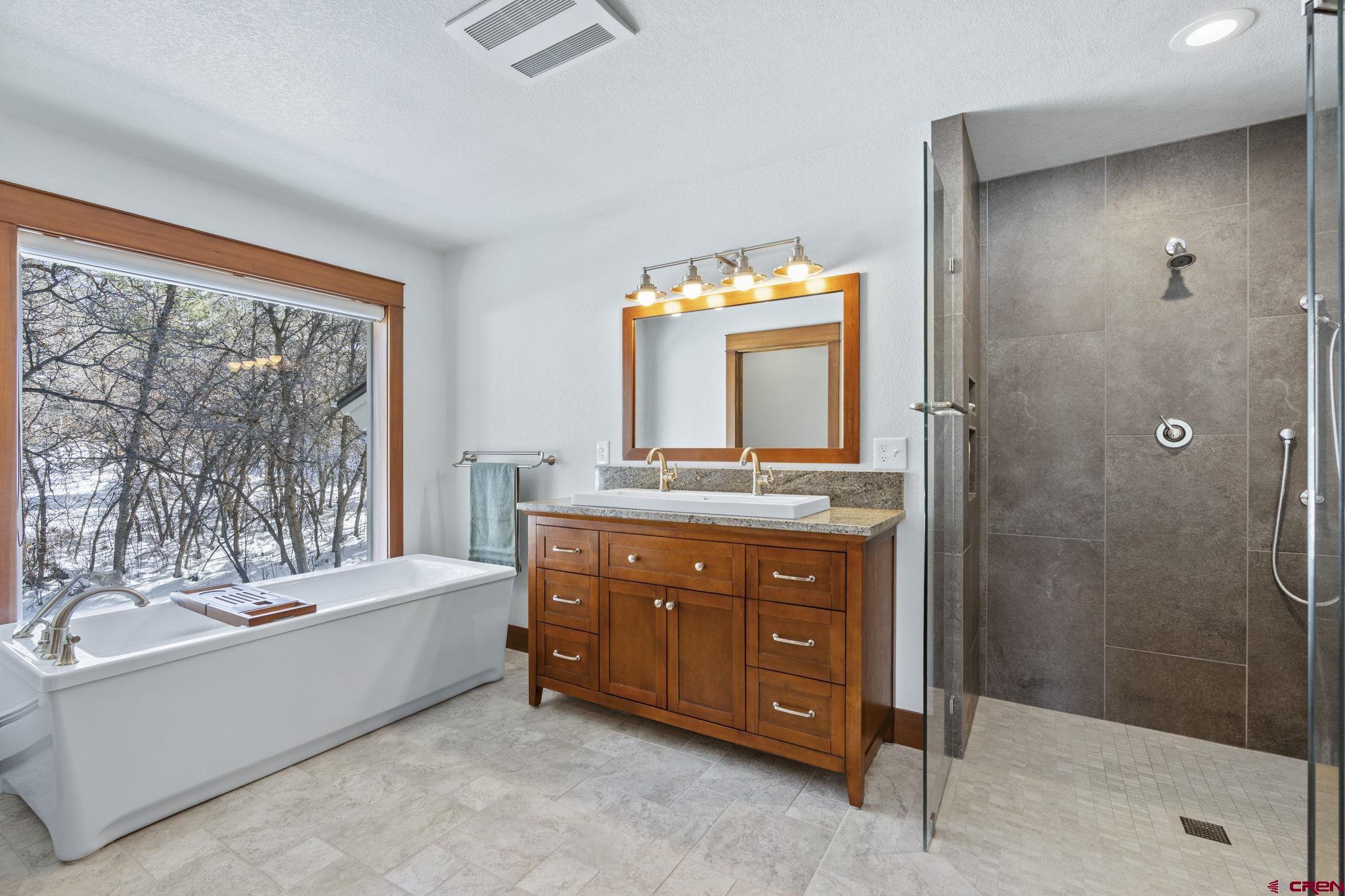 24 Songbird Lane Durango, CO 81301 - Photo 32 of 45 a bathroom with a tub a double vanity sink and a mirror
