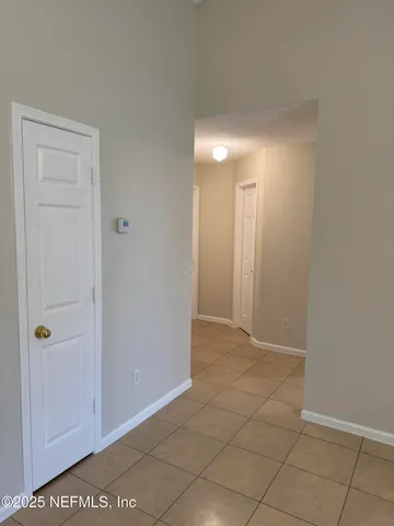 a view of an empty room with window and chandelier fan