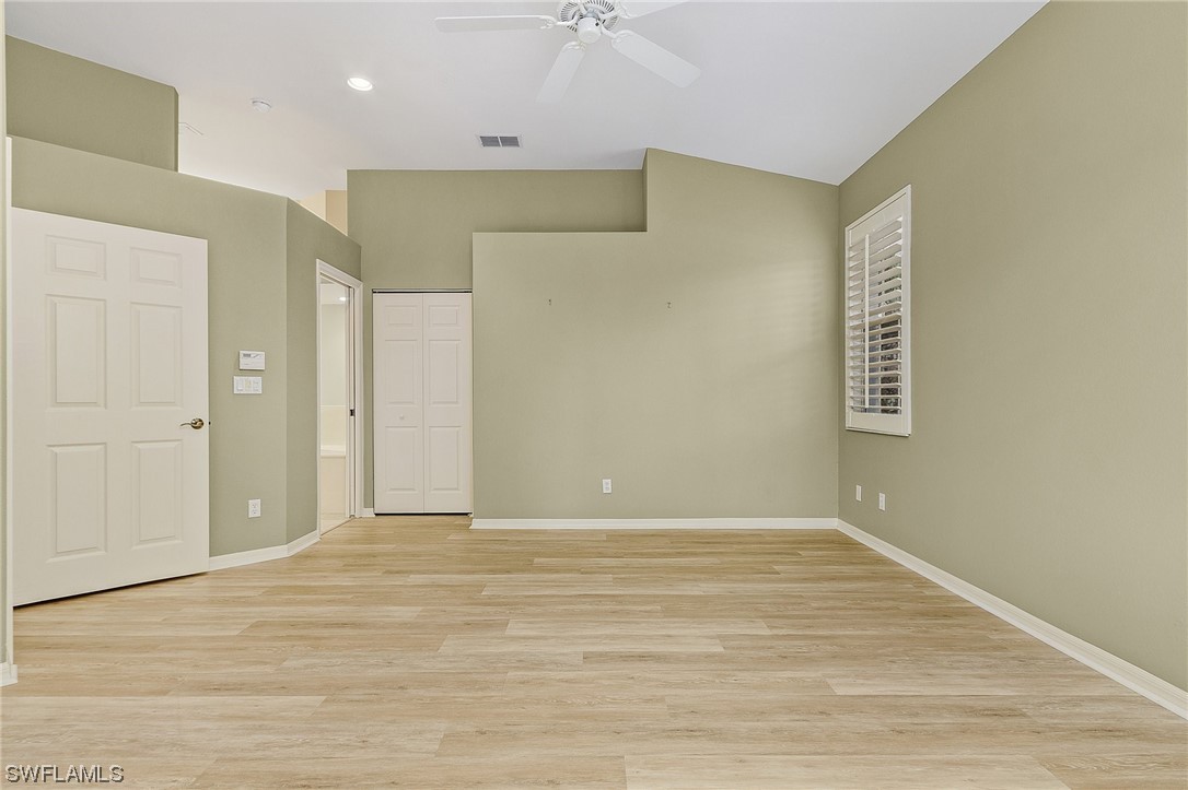 10321 Cape Roman Road, Unit 102 Estero, FL 34135 - Photo 17 of 33 a view of an empty room with wooden floor and a ceiling fan