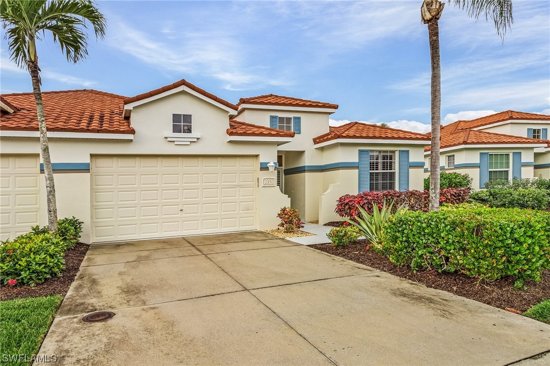 10321 Cape Roman Road, Unit 102 Estero, FL 34135 - Photo 23 of 33 a view of a white house with large windows and flower plants