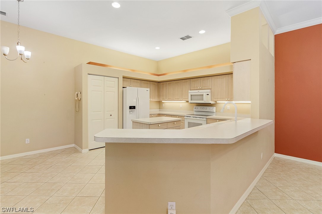 10321 Cape Roman Road, Unit 102 Estero, FL 34135 - Photo 9 of 33 a kitchen with kitchen island a sink stainless steel appliances and cabinets