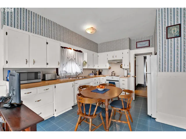 a kitchen with stainless steel appliances a table chairs and a refrigerator