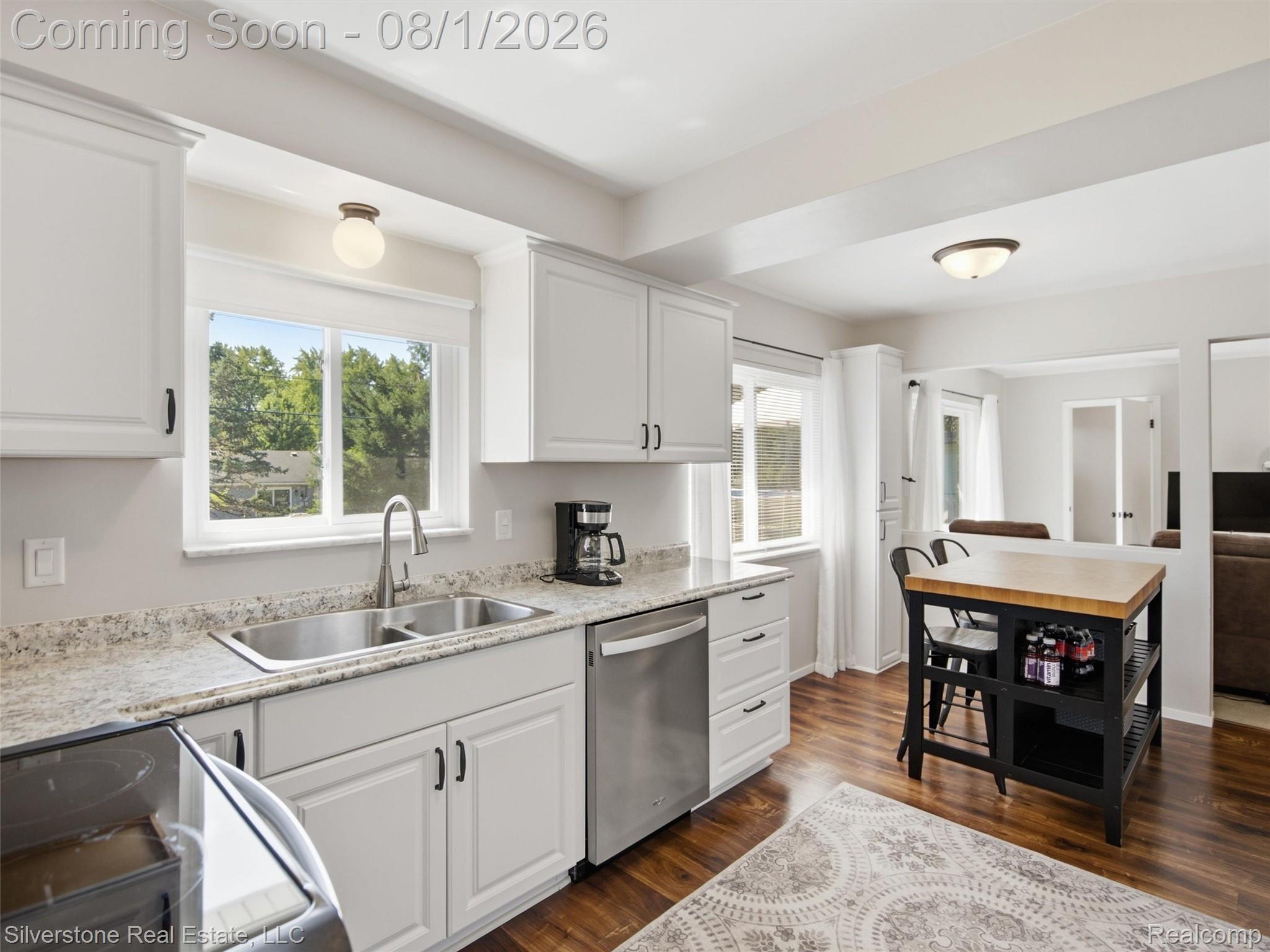 2135 Wayward Drive Rochester, MI 48309 - Photo 18 of 55 Kitchen featuring white cabinetry with dark hardware, a stainless steel sink with a gooseneck faucet, light-toned countertops, and wood-finish flooring