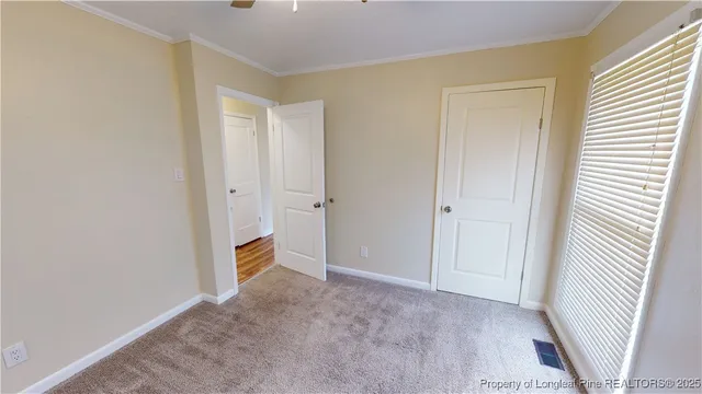 a view of an empty room with closet and a window