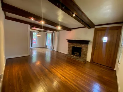 a view of an empty room with wooden floor and a fireplace