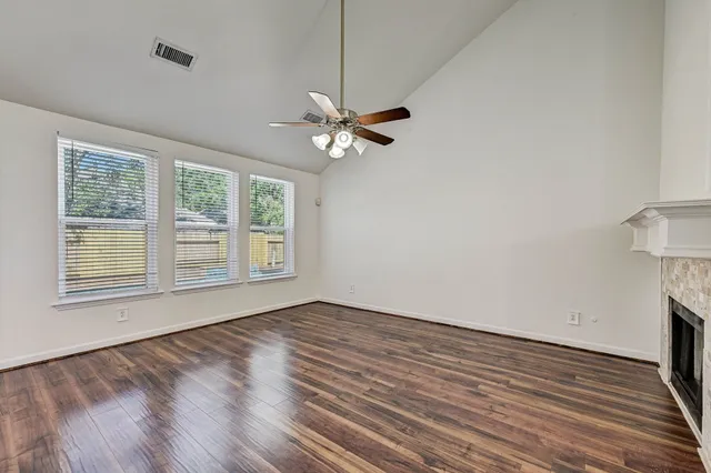 a view of an empty room with a window and wooden floor