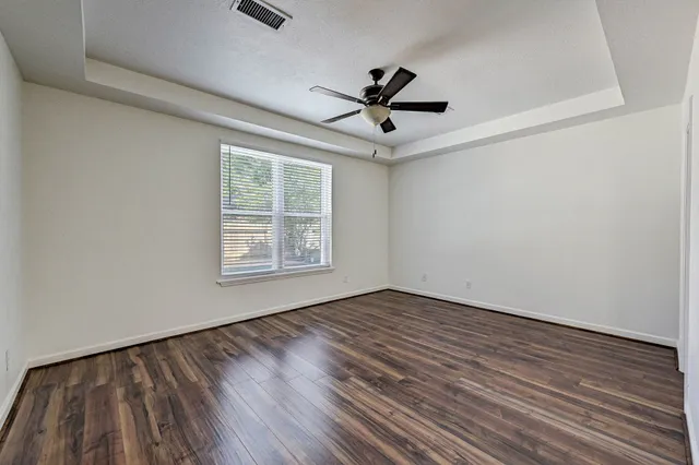 a view of empty room with wooden floor and fan