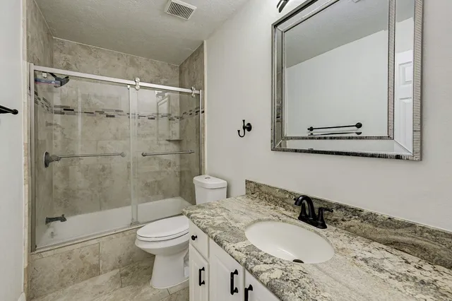 a bathroom with a granite countertop sink toilet a mirror and shower