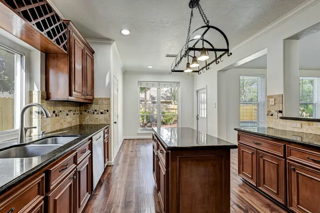 a kitchen with granite countertop cabinets a sink a window and stainless steel appliances