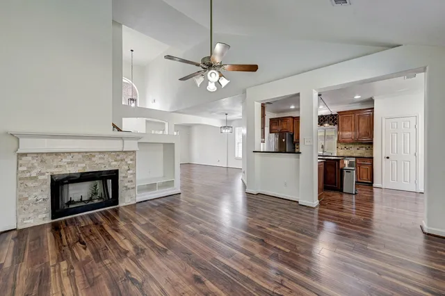 a view of a kitchen and an empty room with wooden floor a fireplace