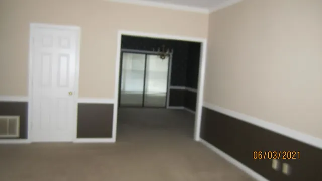 a view of a brick house with plants and large trees